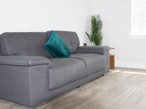 a gray couch with a blue pillow in a living room at 4 Mote View-Uk37497 in Sandhead