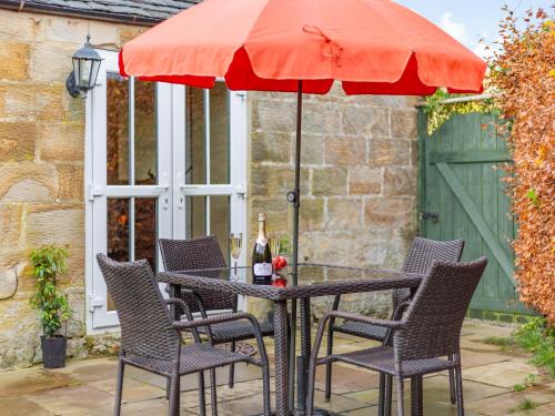 a table with chairs and an umbrella on a patio at Cowslip Cottage in Swarland