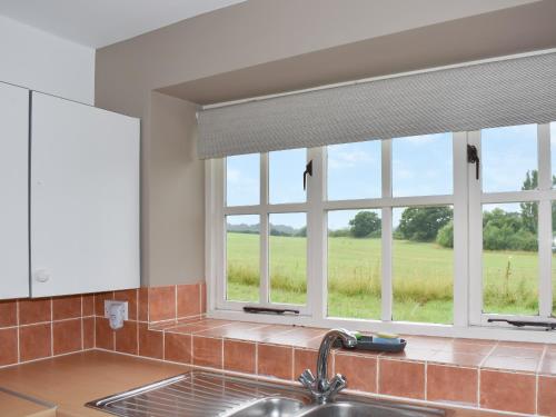 a kitchen with a sink and a window with a view of a field at The Cottage At Canefield Farmhouse in Mottisfont