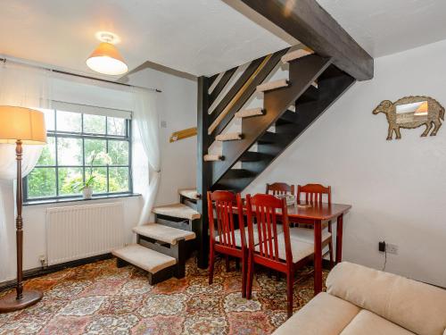 a living room with a table and a spiral staircase at Ginny's Cottage in Haworth