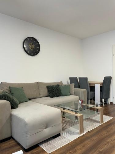 Una sala de estar con un sofá y un reloj en la pared. en TM Apartment Prijedor, en Prijedor