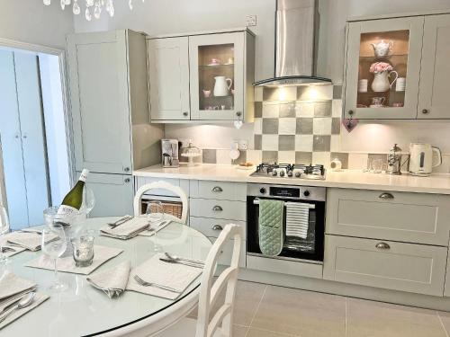a white kitchen with a table and a stove at Lavender Cottage in Frinton-on-Sea