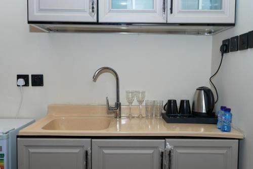een keuken met een wastafel en een aanrecht met glazen bij رايز العارض للشقق المخدومة in Riyad