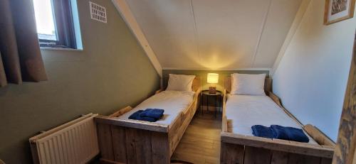 two twin beds in a small room with a window at Gezellig 6pers Familiehuis grote tuin met BBQ aan meer Gelderland in Ewijk