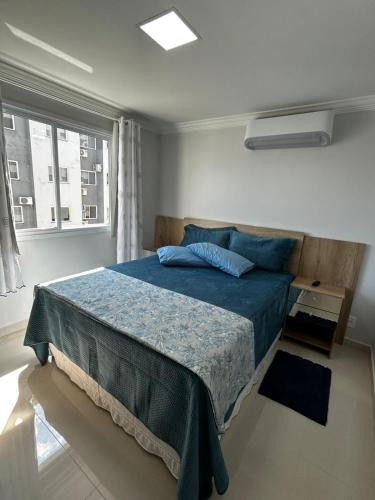 ein Schlafzimmer mit einem Bett mit blauen Laken und einem Fenster in der Unterkunft AP Novinho! à 150m das piscinas! 3 ar cond - churrasqueira in Piratuba