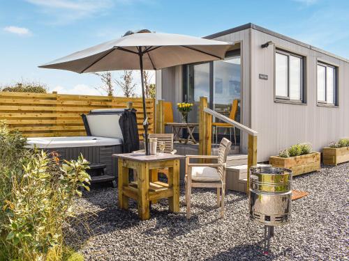 a table with an umbrella next to a tiny house at Uk39216 - Swn Y Mor in Holyhead