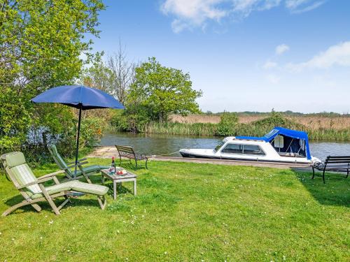 une table et des chaises avec un parasol et un bateau dans l'établissement Riversdale Cottage, à Neatishead