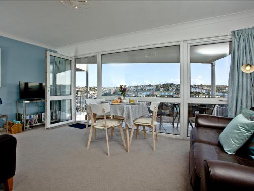 ein Wohnzimmer mit Tisch und Stühlen und einem Balkon in der Unterkunft Turnstone - 2 Linden Court in Brixham