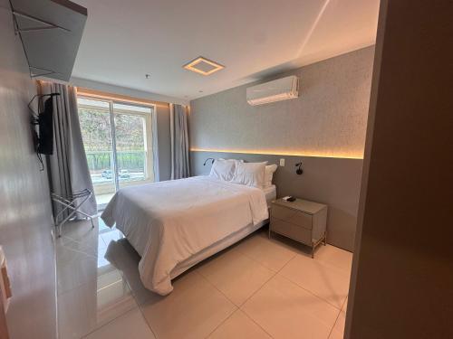 ein Schlafzimmer mit einem weißen Bett und einem Fenster in der Unterkunft Condominio Brisas do Lago in Brasilia