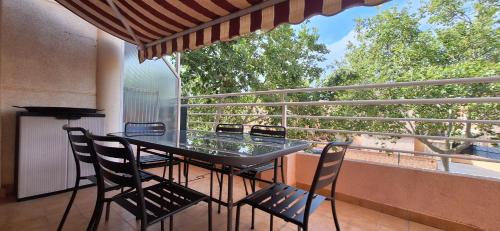 a table and chairs on a balcony with a view of trees at Vacaciones en el mar in Puerto de Sagunto