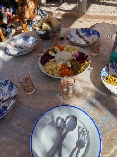 a table with plates of food and spoons and forks at GITE ROURAL TATIOUINE Midelt in Tattiouine