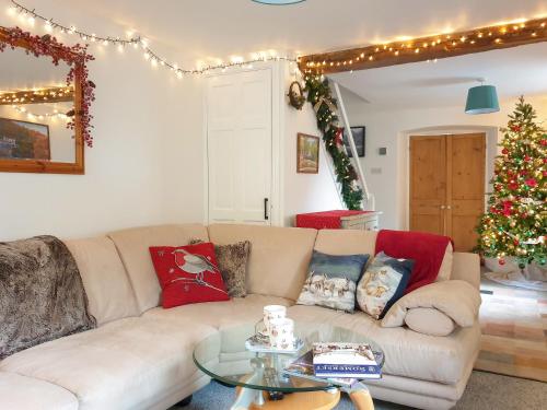 ein Wohnzimmer mit einer Couch und einem Weihnachtsbaum in der Unterkunft Christmas Cottage in Cheddar