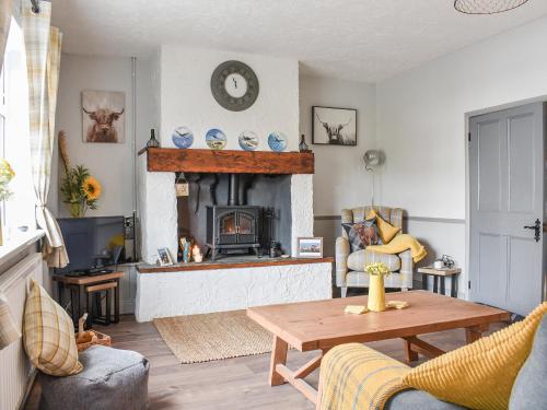 a living room with a fireplace and a table at Elms Cottage - Sadberge in Long Newton