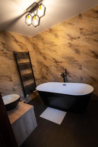 a bathroom with a black tub and a wooden wall at Chalet Sonnenhang in Fundu Moldovei