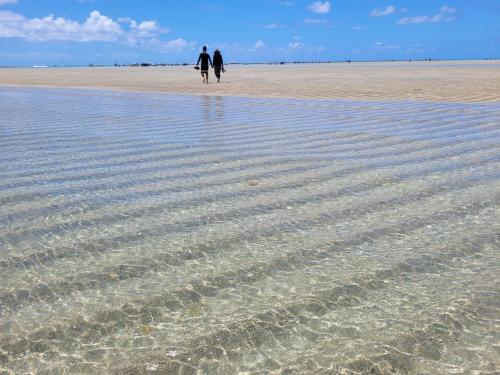 two people walking on a beach with water at Casa Marémar Maragogi in Maragogi