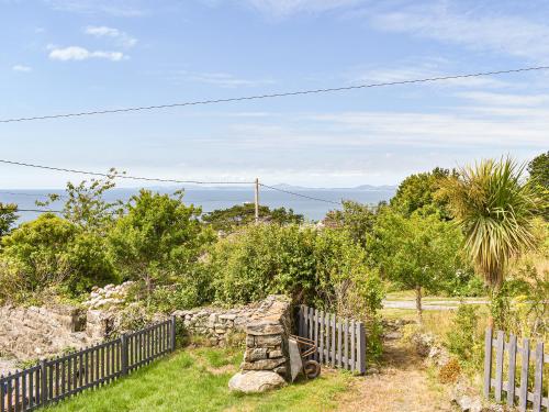 a garden with a fence and the ocean in the background at Bryn Derwen in Llanfair