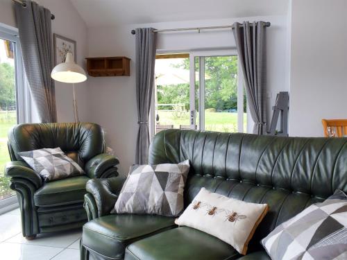 a living room with a green leather couch and chairs at Bumble Lodge in Llynclys