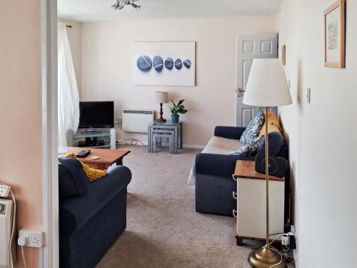 a living room with a blue couch and a table at Brightlands Apartment in Poughill