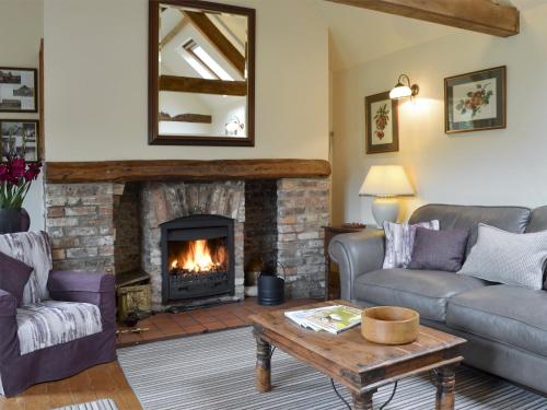 ein Wohnzimmer mit Couch und Kamin in der Unterkunft Wisteria Cottage in Skirpenbeck