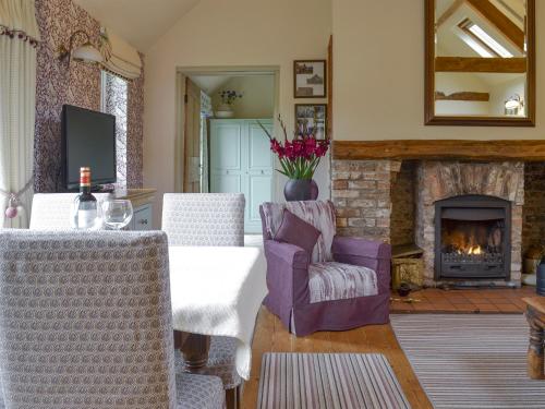 ein Wohnzimmer mit Kamin, Tisch und Stühlen in der Unterkunft Wisteria Cottage in Skirpenbeck