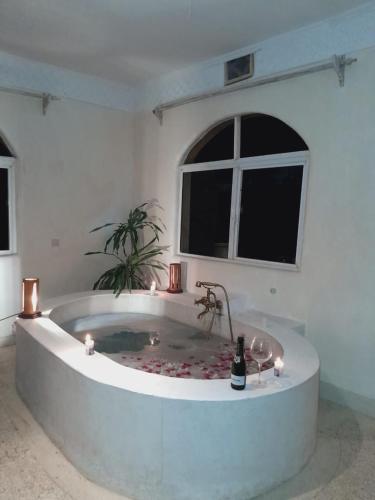 a large white room with a tub with a bottle of champagne at Villa Paradise in Diani Beach