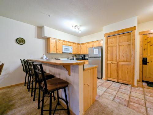 a kitchen with wooden cabinets and a bar with stools at Tenderfoot Lodge 2626 by SummitCove Lodging in Colorado in Keystone