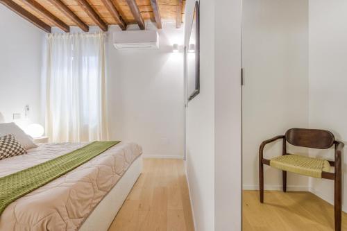 a small bedroom with a bed and a chair at Fumo di Lambrusco - Rua Frati 34 - Boutique Apartment in Modena