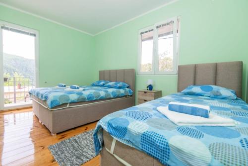 two beds in a room with two windows at GALIOT Apartment in Škaljari