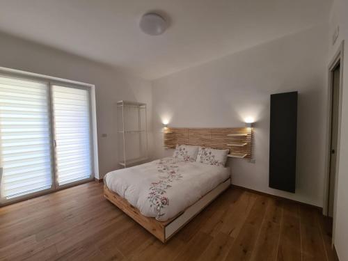Cette chambre comprend un lit avec des draps blancs et du parquet. dans l'établissement La Casa di Nonna, à Conversano