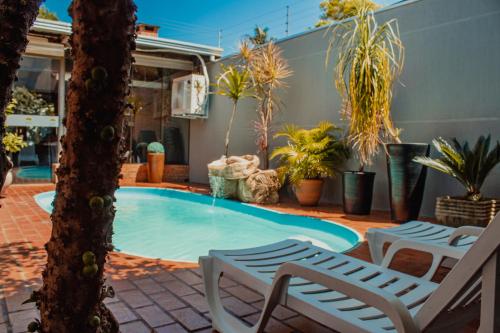 a swimming pool with two lounge chairs and plants at Pousada Nanai in Foz do Iguaçu