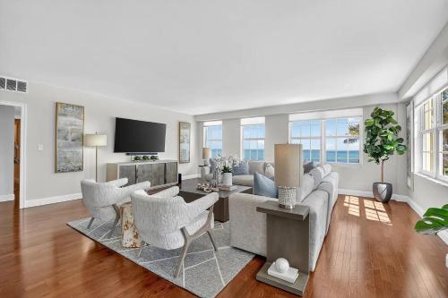 a living room with a couch and chairs and a tv at Direct Oceanfront Three-Bedroom Luxury Apartment with Large Terrace in South Palm Beach