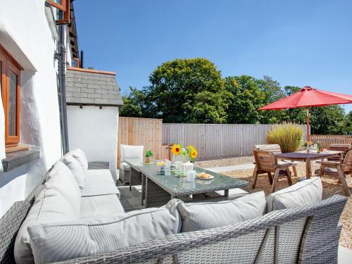 eine Terrasse mit einer Couch und einem Tisch mit Stühlen in der Unterkunft Four Seasons Cottage in Langtree