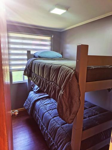 a small bedroom with a bunk bed and a window at Tu Refugio Quellon in Quellón