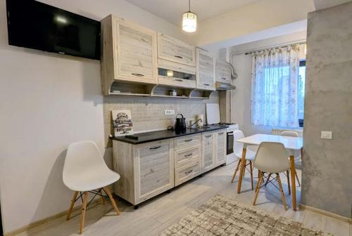 a kitchen with white cabinets and a table and chairs at Apartament Complex Rezidential Magnolia Bariera Valcii in Craiova