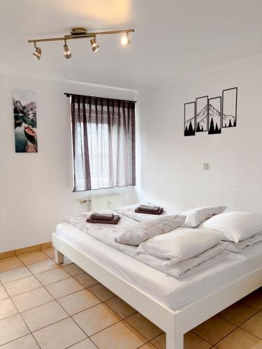 a white bed in a white room with a window at Apartment 71 Ettelbrück in Ettelbruck
