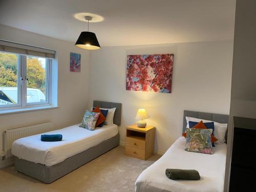 ein Schlafzimmer mit zwei Betten und einem Fenster in der Unterkunft Warm & Cosy 4 Bed Cambridge House w Parking Garden & High Speed WIFI in Milton