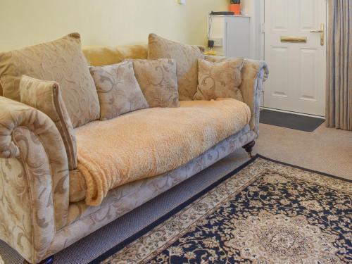 eine Couch in einem Wohnzimmer mit einem Teppich in der Unterkunft Gold Cottage in Swaffham