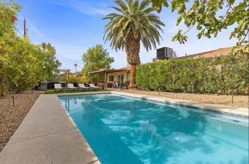 a swimming pool in front of a house with a palm tree at Stylish home with pool and spa in Las Vegas