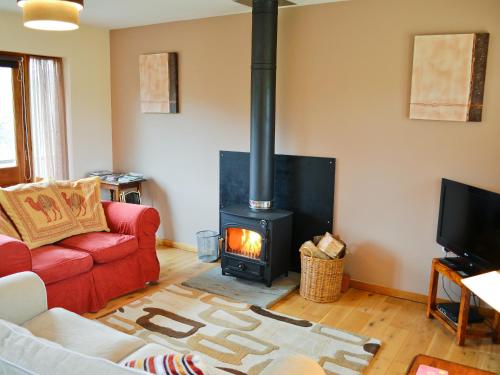 a living room with a fireplace and a red couch at Church View - 24731 in Bearsted
