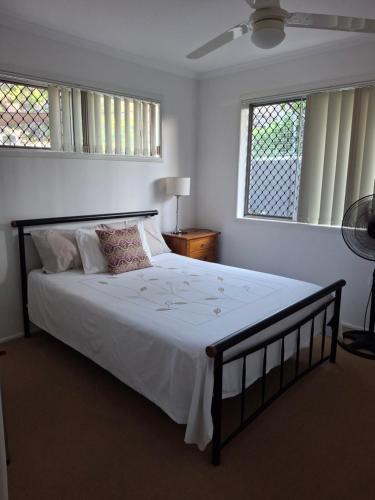 GladstoneにあるSandi's House For twoのベッドルーム1室(大型ベッド1台、白いシーツ、窓2つ付)