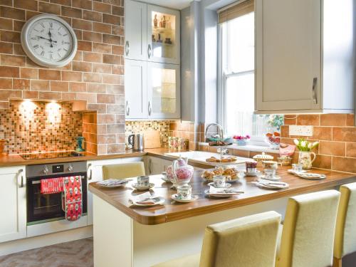 a kitchen with a table and a clock on the wall at Church View in Skipton