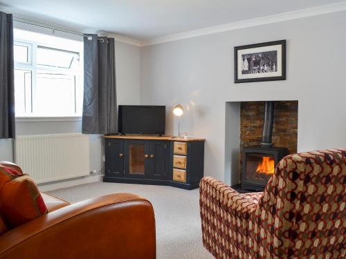 ein Wohnzimmer mit Kamin und Fernseher in der Unterkunft Three Creeks Cottage in Portknockie