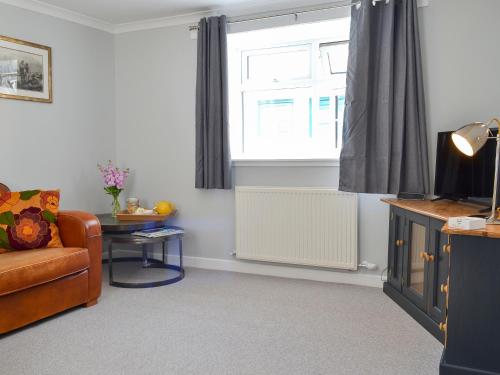 ein Wohnzimmer mit einer Couch und einem Fenster in der Unterkunft Three Creeks Cottage in Portknockie