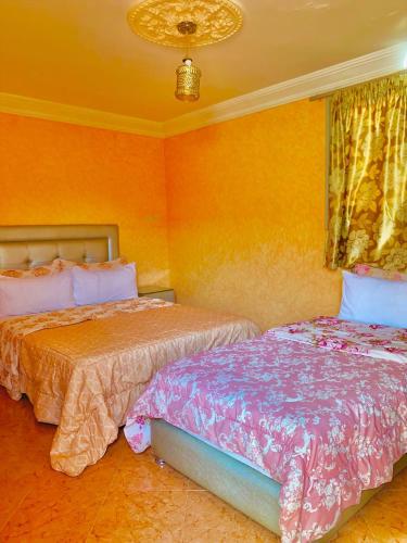 two beds in a bedroom with orange walls at La paillade in Oulad Barrehil