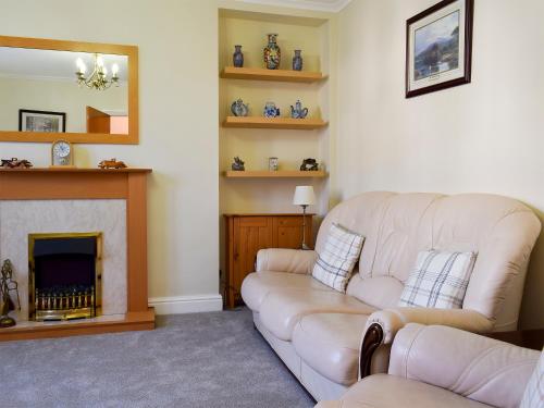 ein Wohnzimmer mit Couch und Kamin in der Unterkunft Alexandra Cottage in Windermere