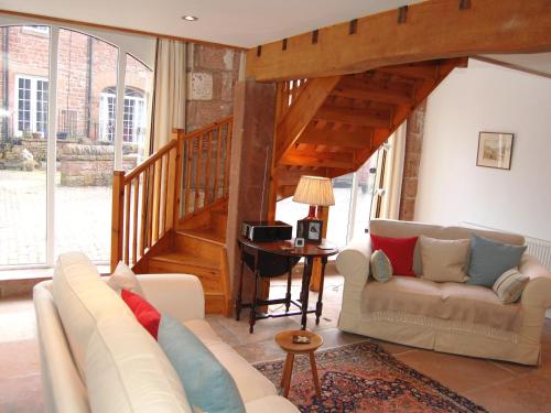 a living room with a couch and a staircase at Woodstore Cottage in Lazonby