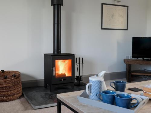 a stove in a living room with a table with cups at The Foundary - Uk36319 in Whitchurch