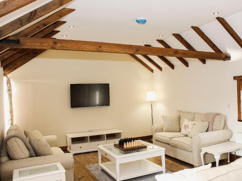 een woonkamer met twee banken en een tv bij The Cart Shed in Tickton