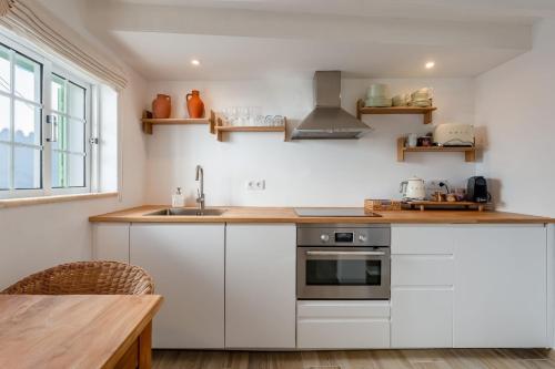 a kitchen with white cabinets and a sink at Brisa do Sul in Porches