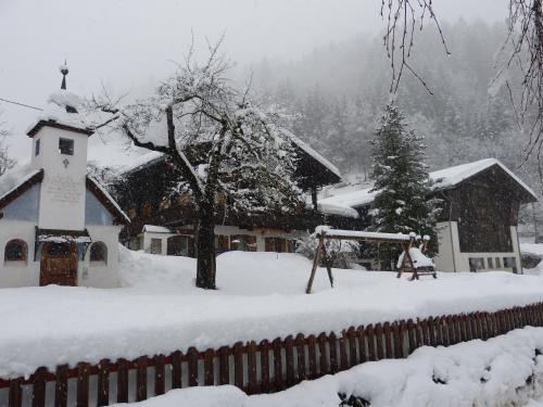 a church covered in snow in front of a fence at Ferienwohnungen am Bauernhof in Rangersdorf